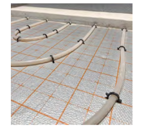Underfloor heating pipes secured with 40mm pipe clips on aluminium thermal insulation foil with printed grid, ready for screed installation.